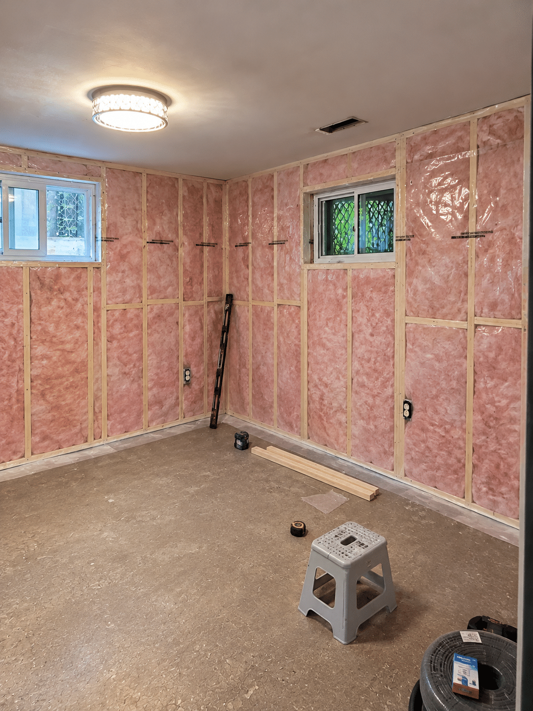 Interior wall framing and fiberglass batt insulation installation with polyethylene vapour barrier
