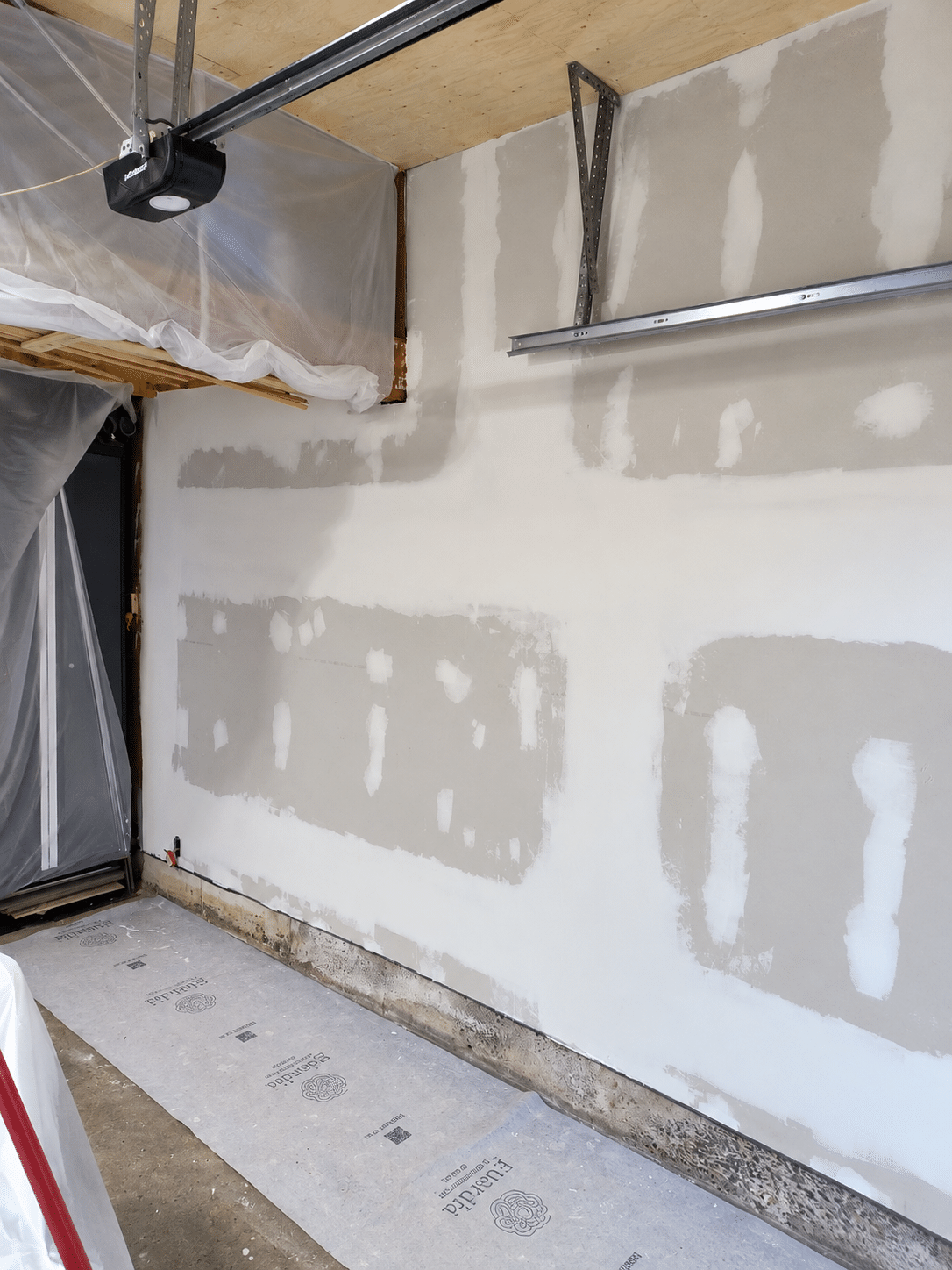 Garage drywall repair and finishing with taped joints, applied joint compound, and surface preparation